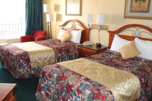 Una habitación de hotel con dos camas y una silla roja. en Grand Prix Motel Beach Front, en Daytona Beach