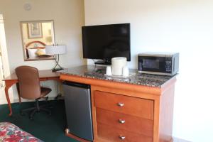 a room with a desk with a microwave and a television at Grand Prix Motel Beach Front in Daytona Beach