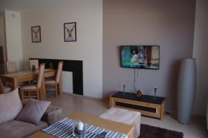 a living room with a couch and a tv on a wall at Apartamenty Plaza Słupca in Słupca