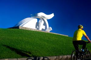 a man riding a bike in front of a sculpture at RK City Center in Las Palmas de Gran Canaria