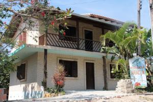 a house with a balcony and a palm tree at Residencial Aracuã in Bombinhas