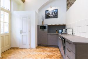 Il comprend une cuisine avec des murs blancs et du parquet. dans l'établissement Apartment Nebovidy I - Free Parking - Terrace - Air Conditioning, à Prague