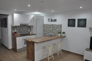 a kitchen with white cabinets and a counter with stools at La Casita De Angela in Frigiliana +5 photos