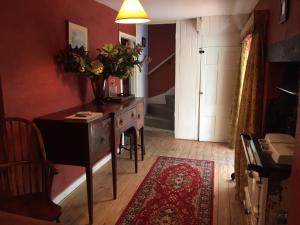 a room with a desk and a table with a vase of flowers at Bittles Cottage in Dorchester