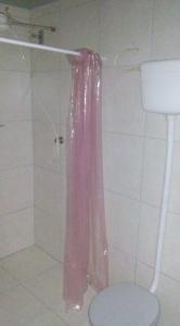 y baño con ducha y cortina de ducha rosa. en Solar Dona Irma, en Guaratuba