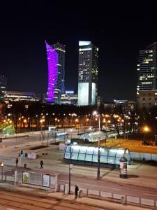 un perfil urbano por la noche con un edificio púrpura en Coser Apartamenty Centrum 1, en Varsovia
