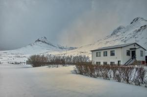 una casa blanca frente a una montaña cubierta de nieve en Sudavik guesthouse en Súðavík