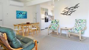 a living room with a couch and a table and chairs at Seaspray in Merimbula