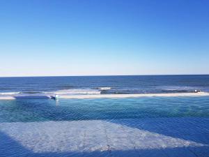 a pool of water with a beach in the background at Los Pinos Pinamar in Pinamar