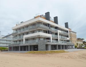 a large building on the beach next to the sand at Los Pinos Pinamar in Pinamar