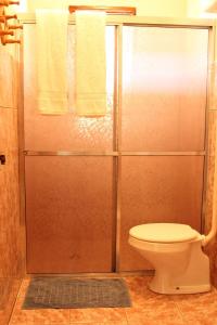 a bathroom with a shower with a toilet and a glass door at Fazenda Pousada Cachoeira do Flávio in São Thomé das Letras +42 photos