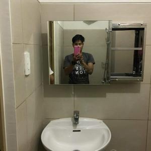 un homme prenant une photo de lui-même dans un miroir de salle de bains dans l'établissement Sweethearts place 1 at wind residences, à Tagaytay