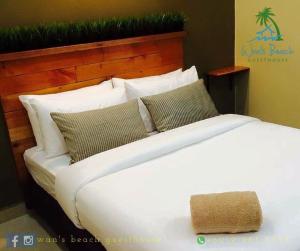 a large bed with white sheets and pillows at Wan's Beach Guest House in Dungun