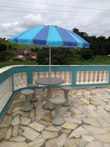 a table and chairs with a blue umbrella at Chácara Oliveira in Socorro