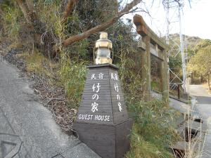 una señal para una casa de huéspedes al lado de una carretera en Minshuku Takenoya, en Naoshima