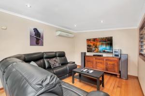 a living room with a leather couch and a table at Edge Hill Holiday Home / Cairns in Edge Hill