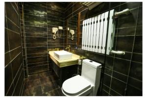 Baño de azulejos negros con aseo y lavamanos en Pingyao Zheng Garden Inn, en Pingyao