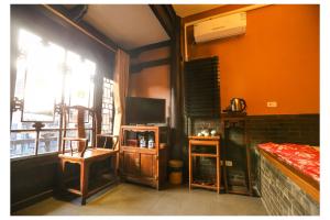 a living room with a tv and a window at Pingyao Zheng Garden Inn in Pingyao