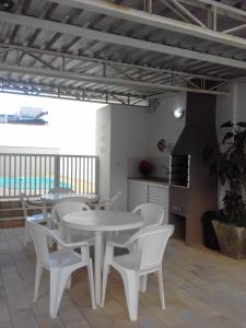 ein Esszimmer mit weißen Tischen und weißen Stühlen in der Unterkunft Apartamento 3 quartos próximo a Praia Grande com ar condicionado in Ubatuba