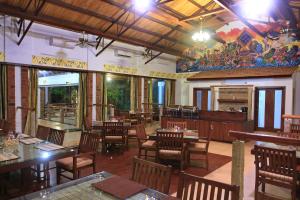 PālameduKadambavanam Ethnic Village Resort的一间有木桌椅和壁画的餐厅