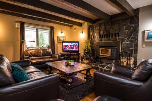 a living room with leather furniture and a fireplace at Bella Coola Eagle Lodge in Bellakula