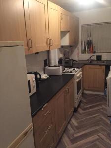 a kitchen with wooden cabinets and a white refrigerator at Double Room Home Stay Manchester in Manchester