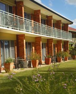 a building with a balcony and tables and chairs at Shelly Beach Motel in Hervey Bay