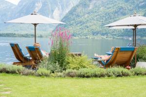 two people sitting in lawn chairs next to a lake at Hallstatt Hideaway - Adults only in Hallstatt