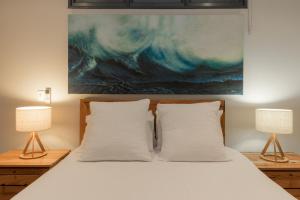 a bedroom with a bed with two lamps and a painting at Salt The Studio in Kalbarri