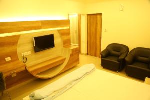 a room with two chairs and a flat screen tv at Samarth Residency in Hospet