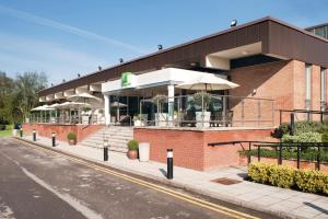 un bâtiment avec des parasols sur le côté d'une rue dans l'établissement Holiday Inn Rugby-Northampton M1 Jct18, an IHG Hotel, à Crick