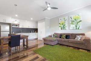 a living room and kitchen with a couch and a table at Pandanus Spa Cottage in Coolum Beach
