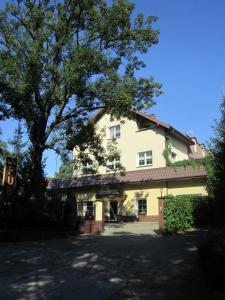 una grande casa bianca con un grande albero di Hotel Korona a Słubice