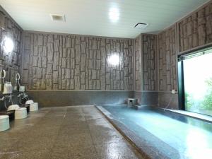 een zwembad in een kamer met houten wanden bij Hotel Route-Inn Matsusaka Ekihigashi in Matsuzaka