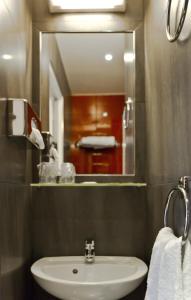 La salle de bains est pourvue d'un lavabo et d'un miroir. dans l'établissement L'Olympique 1924, à La Garenne-Colombes
