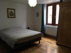 a bedroom with a bed and a window and a chandelier at Le P'retzel & Le Sticksy in Riquewihr