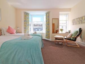 a bedroom with two beds and a chair and a mirror at Breakers Point in St Ives