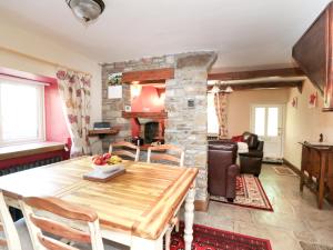 a living room with a table and a stone fireplace at Rose Cottage in Chinley