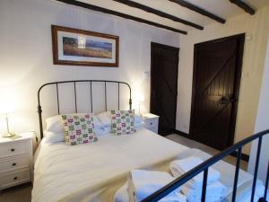 a bedroom with a bed with white sheets and pillows at Laurel Cottage in Ulverston