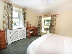 1 dormitorio con cama, escritorio y ventana en Rose Cottage, en Chinley