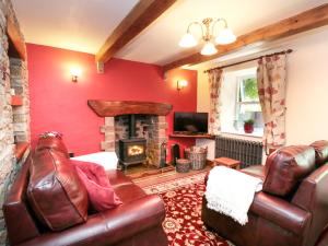 a living room with a leather couch and a fireplace at Rose Cottage in Chinley