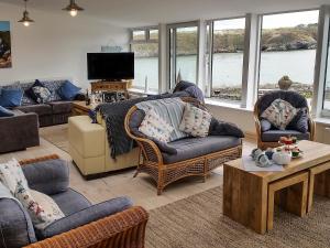 uma sala de estar com sofás e cadeiras e uma televisão em Angorfa em Cemaes Bay