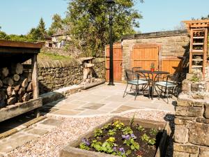 a patio with a table and chairs and a stone wall at Rose Cottage in Chinley