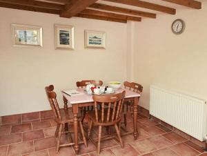 een eetkamer met een tafel en stoelen en een klok bij Cow Byre Cottage in Pickering