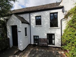 a white house with a bench in front of it at Laurel Cottage in Ulverston