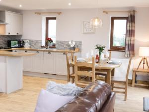 a kitchen and living room with a couch and a table at Gardener's Lodge in Nantwich