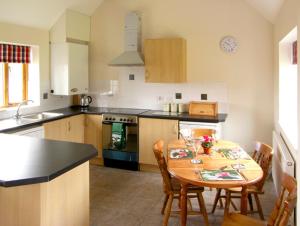 eine Küche mit einem Tisch und Stühlen sowie eine Küche mit einem Waschbecken in der Unterkunft The Roost in Stratford-upon-Avon