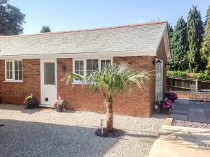 a brick house with a palm tree in front of it at The Hideaway in Verwood