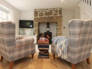a living room with two chairs and a fireplace at The Old Forge, St Just in St. Just
