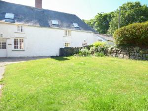 a white house with a stone wall and a yard at Farm Cottage in Saint Erth